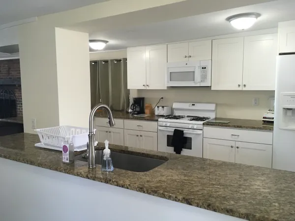 a kitchen with granite countertop a sink stove and cabinets