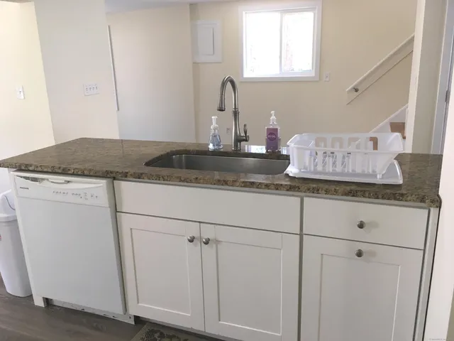 a kitchen with granite countertop white cabinets and a sink