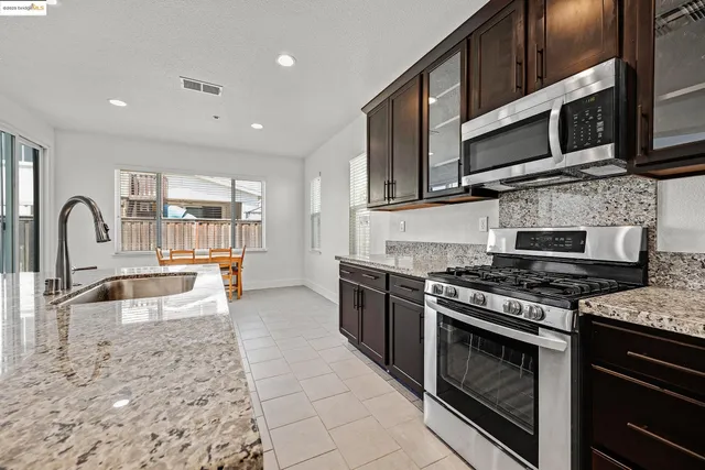 a kitchen with stainless steel appliances granite countertop a stove a sink and a microwave