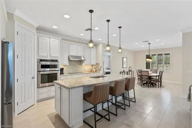 a kitchen with kitchen island a dining table chairs and white cabinets