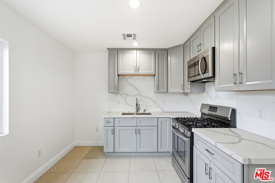 18149 Welby Way Reseda, CA 91335 - Photo 18 of 50 a kitchen with stainless steel appliances granite countertop a sink stove oven and white cabinets