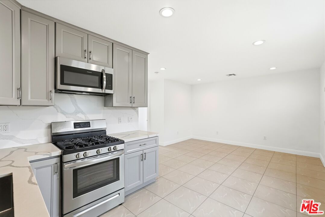 18149 Welby Way Reseda, CA 91335 - Photo 20 of 50 a kitchen with granite countertop a stove a microwave and cabinets