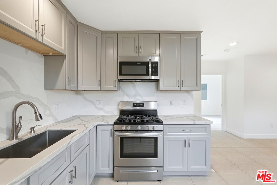 18149 Welby Way Reseda, CA 91335 - Photo 22 of 50 a kitchen with granite countertop white cabinets and stainless steel appliances