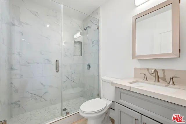 a bathroom with a granite countertop sink a toilet and shower