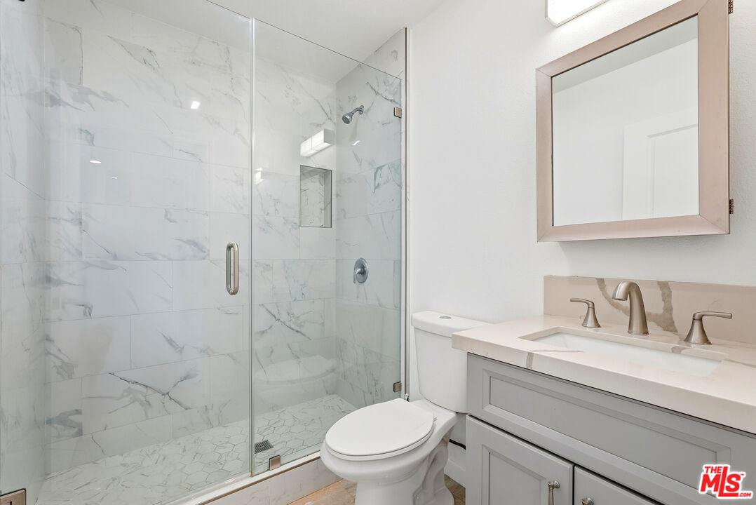 18149 Welby Way Reseda, CA 91335 - Photo 27 of 50 a bathroom with a granite countertop sink a toilet and shower