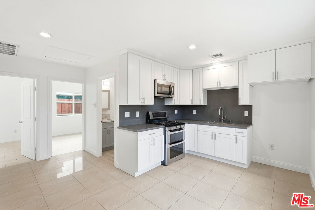 18149 Welby Way Reseda, CA 91335 - Photo 34 of 50 a kitchen with stainless steel appliances granite countertop a stove top oven a sink and a refrigerator