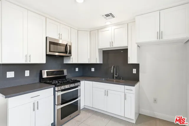 a kitchen with white cabinets and appliances