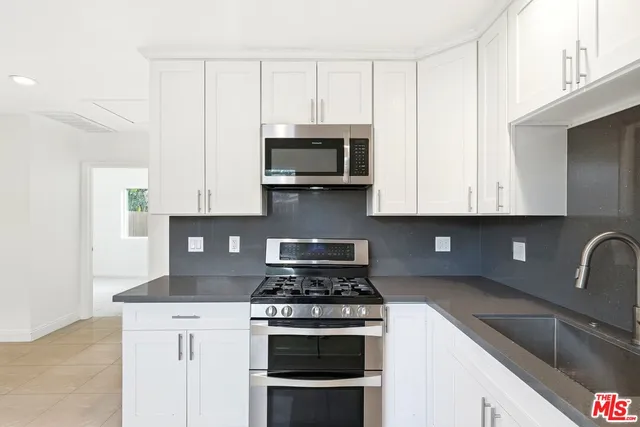 a kitchen with granite countertop white cabinets and black stainless steel appliances