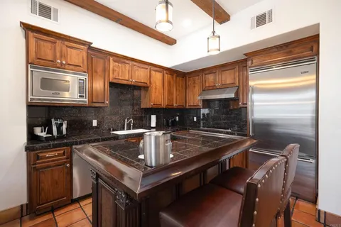 a kitchen with kitchen island granite countertop a sink stove and refrigerator