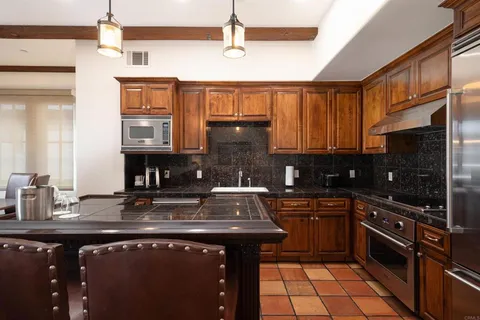 a kitchen with kitchen island granite countertop a sink stainless steel appliances and cabinets
