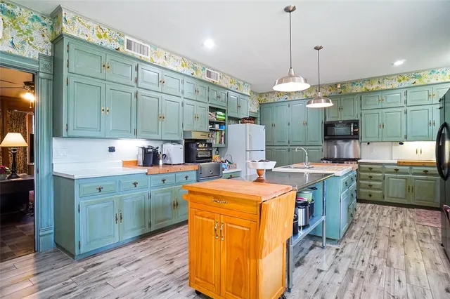 a kitchen with a refrigerator a stove and wooden floor