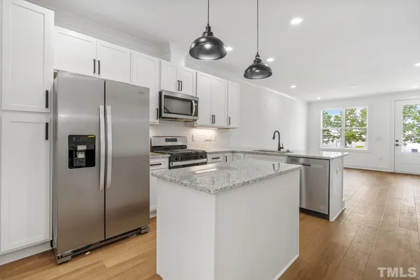 a kitchen with stainless steel appliances granite countertop a refrigerator a stove a sink and a window