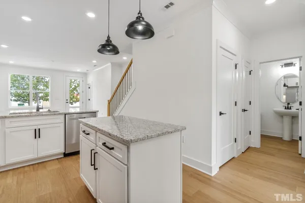 a kitchen with white cabinets and wooden floor