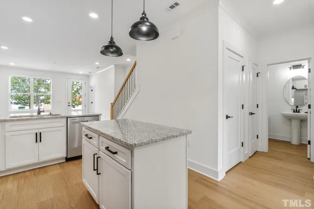 a kitchen with white cabinets and wooden floor