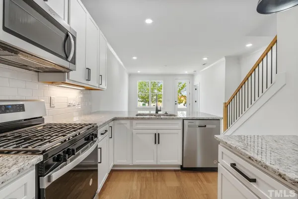 a kitchen with granite countertop a sink stainless steel appliances and cabinets