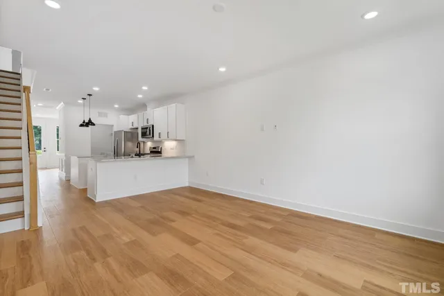 a view of kitchen with kitchen island a sink wooden floor and white cabinets