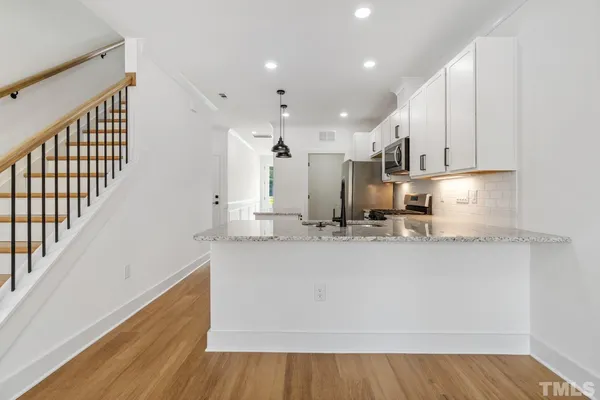 a kitchen with stainless steel appliances granite countertop a sink a stove and a wooden floors