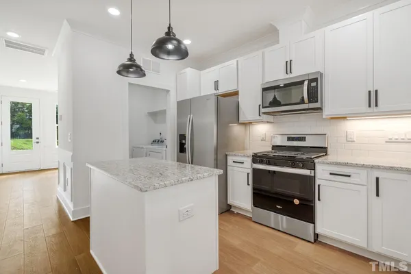 a kitchen with stainless steel appliances granite countertop a sink a stove and a refrigerator