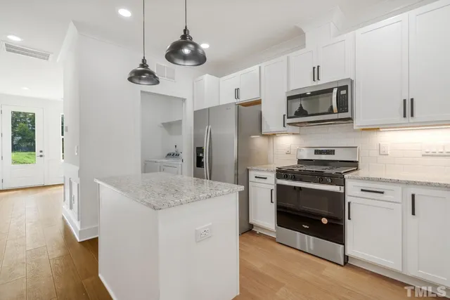 a kitchen with stainless steel appliances granite countertop a sink a stove and a refrigerator