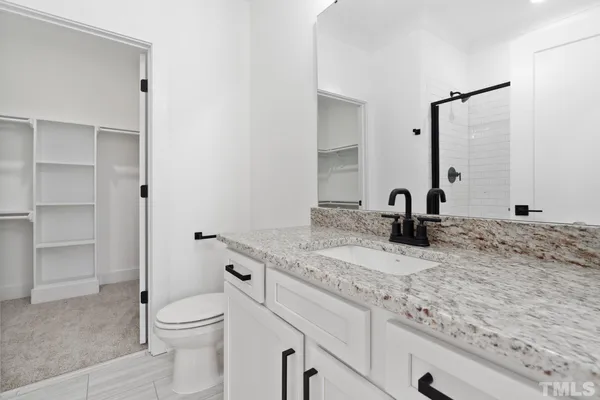 a bathroom with a granite countertop sink toilet and mirror