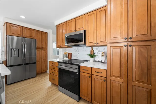 a kitchen with stainless steel appliances granite countertop a refrigerator a stove a sink and dishwasher with wooden floor