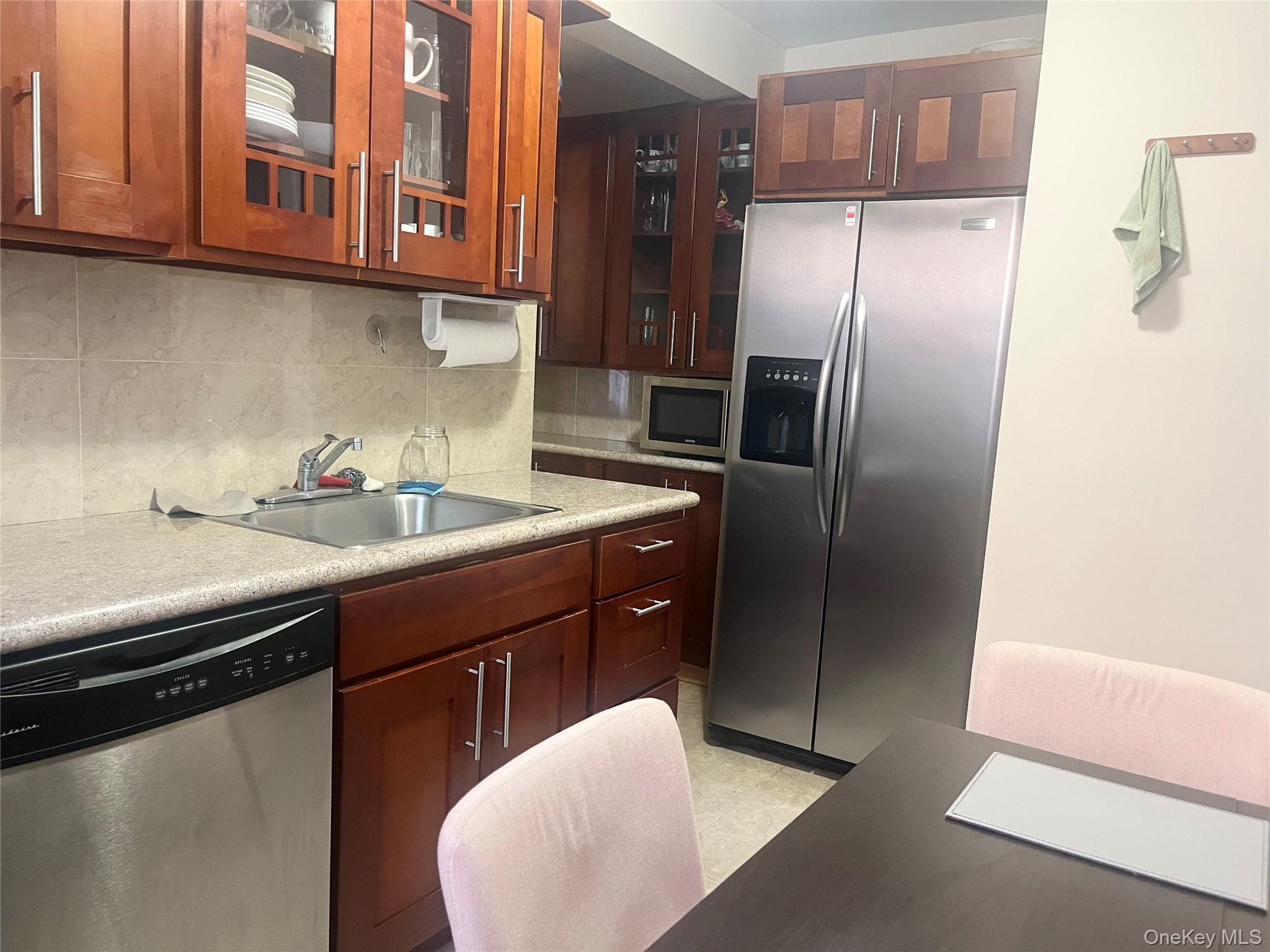 139-15 83rd Avenue, Unit 407 Queens, NY 11435 - Photo 5 of 8 a kitchen with stainless steel appliances granite countertop a sink a refrigerator and a cabinets
