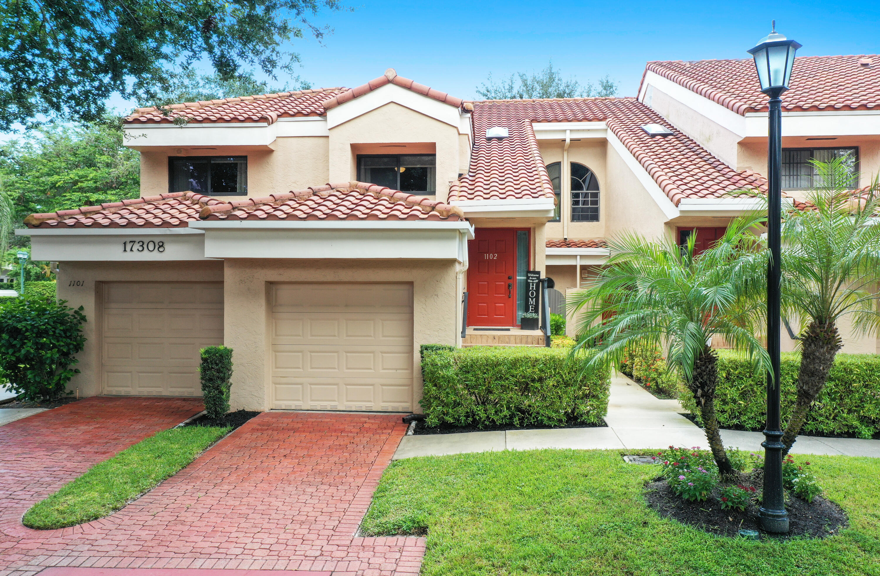 17308 Boca Club Boulevard, Unit 1102 Boca Raton, FL 33487 - Photo 29 of 48 a front view of a house with a yard and garage