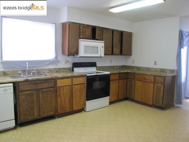1943 South Ranchero Road Valley Springs, CA 95252 - Photo 10 of 23 Kitchen featuring white appliances, plenty of natural light, and brown cabinetry