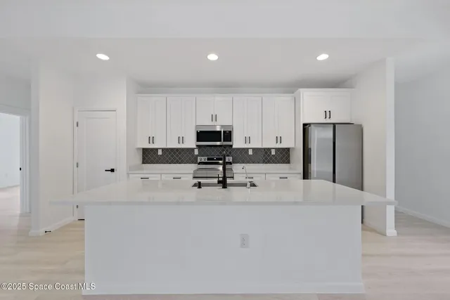 a kitchen with stainless steel appliances granite countertop a refrigerator sink stove and white cabinets