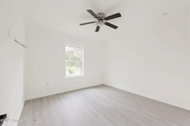 an empty room with a window and a fan