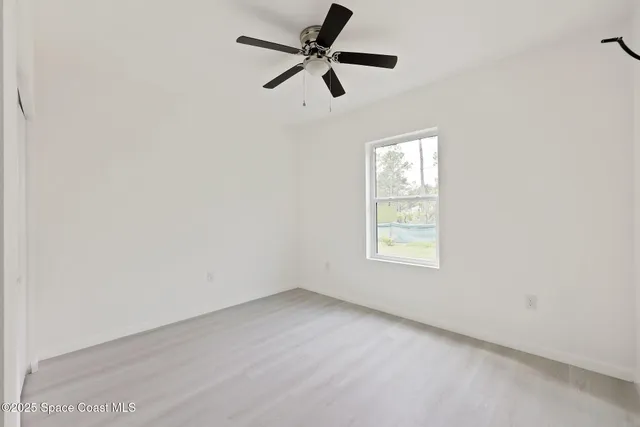 an empty room with a window and a fan