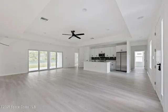 a view of an empty room with window and wooden floor