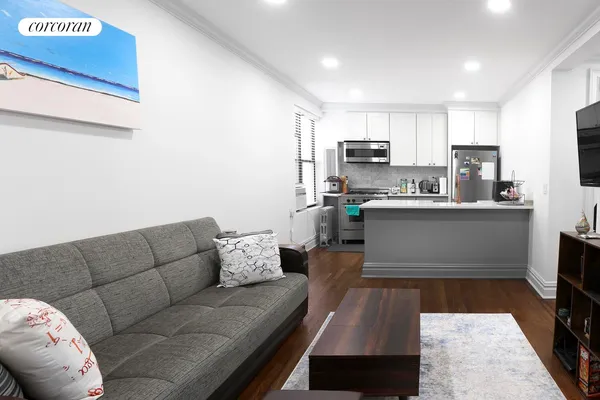 a living room with stainless steel appliances furniture a couch and a kitchen view
