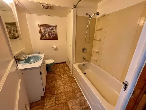 a bathroom with a granite countertop sink a toilet a shower curtain and a bath tub