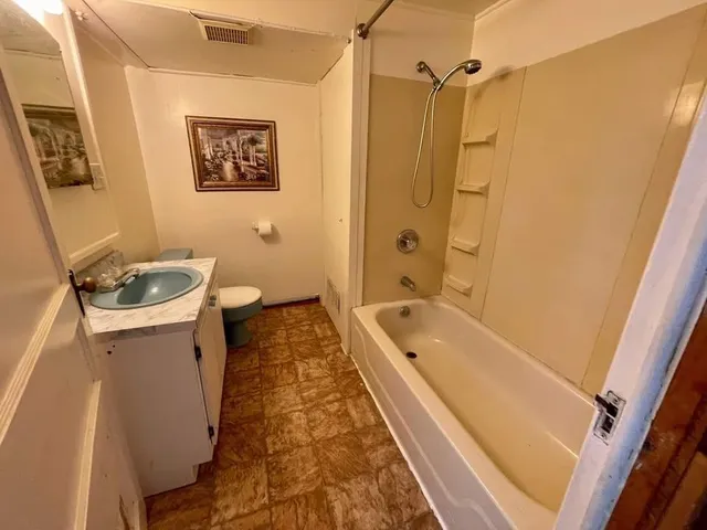 a bathroom with a granite countertop sink a toilet a shower curtain and a bath tub