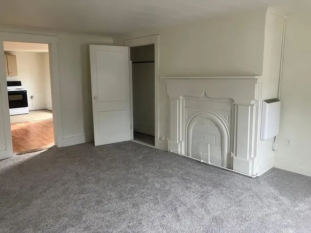 an empty room with a fireplace and windows