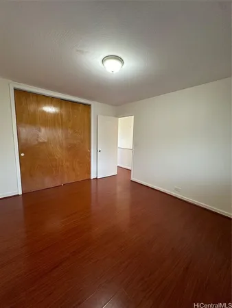 an empty room with wooden floor and windows with curtains