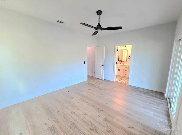 a view of empty room with wooden floor and fan