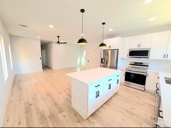 a kitchen with kitchen island a stove a sink a refrigerator and chairs