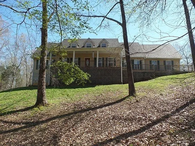 a view of a house with a yard and large tree