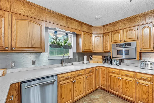 a kitchen with kitchen island granite countertop a sink a stove and a wooden cabinets