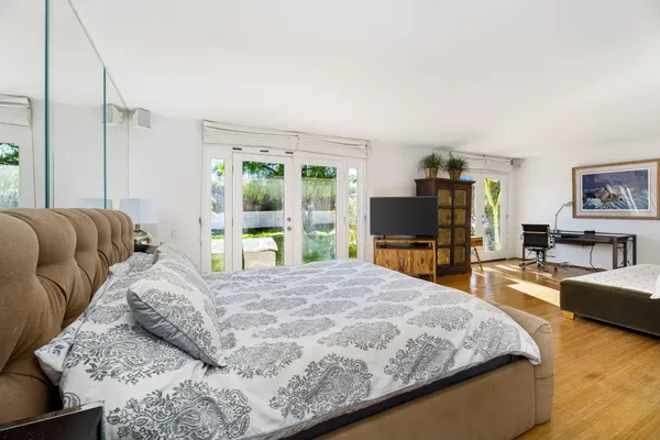 a bedroom with a large bed and a flat tv screen
