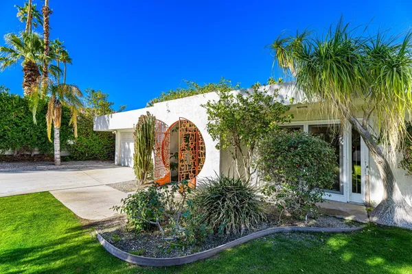 a backyard of a house with plants and palm trees