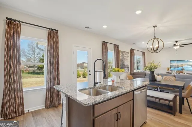 a kitchen with stainless steel appliances granite countertop a sink a stove and a wooden floors