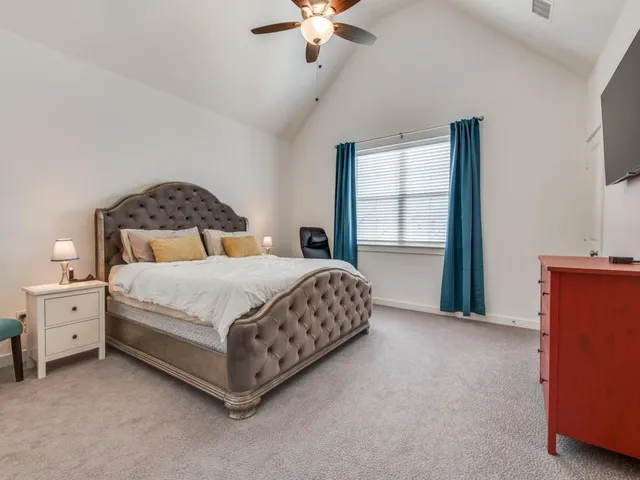 a bedroom with a large bed and a chandelier fan