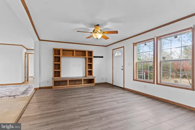 a view of an empty room with a window and wooden floor