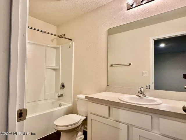 a bathroom with a granite countertop sink a toilet and shower