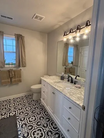 a bathroom with a granite countertop sink toilet and mirror