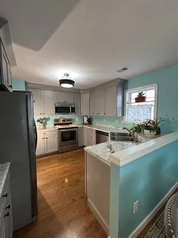 a kitchen with a sink a counter top space stainless steel appliances and cabinets