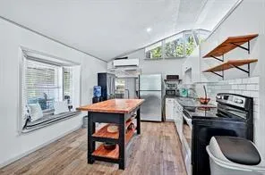 a kitchen with stainless steel appliances granite countertop a stove a refrigerator a sink a dining table and chairs with wooden floor